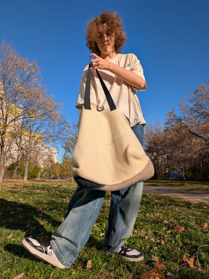 Person showing the plain backside of a functional handmade handbag with original designer patchwork at the front.