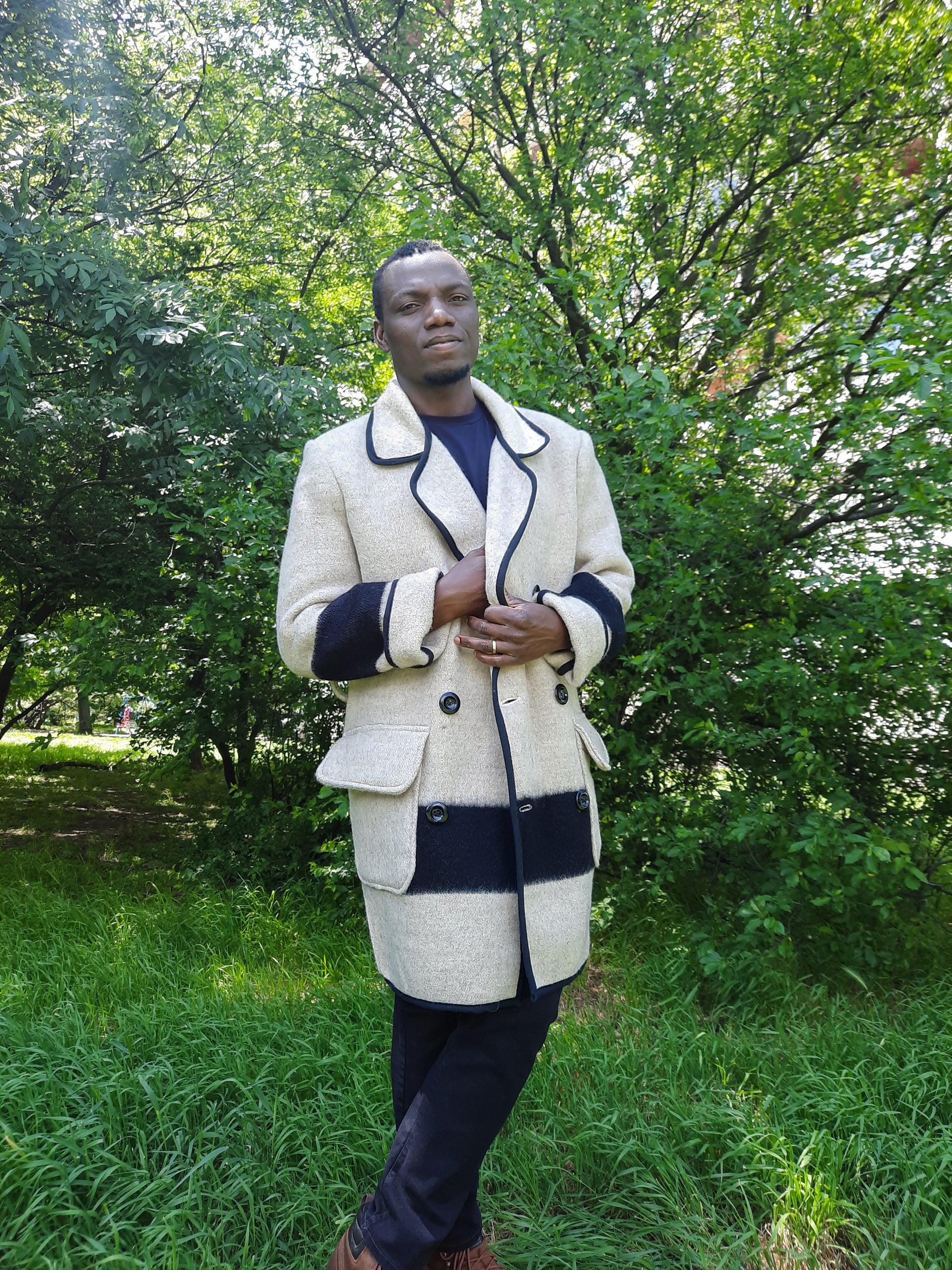 Man wearing an upcycled gray wool blanket peacoat with black stripes, double breasted button closure amd front patched pockets. 