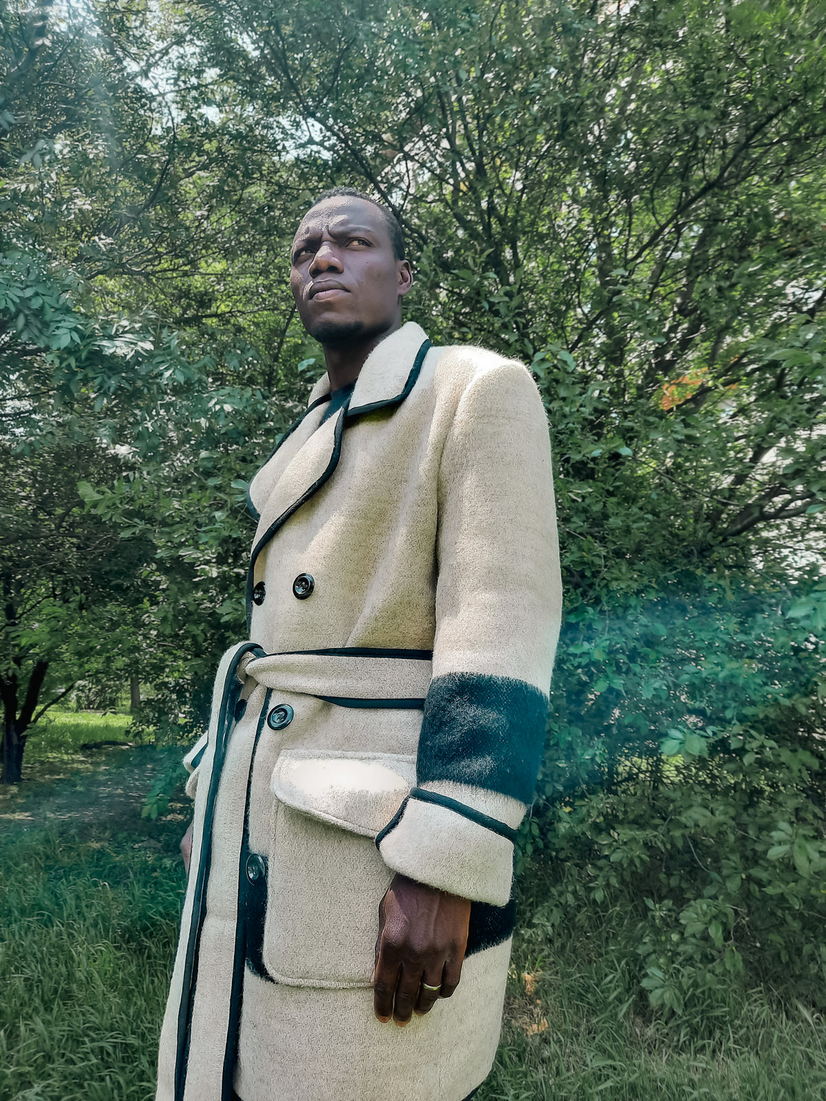 Man wearing an upcycled gray wool blanket peacoat with black stripes, double breasted button closure amd front patched pockets. 