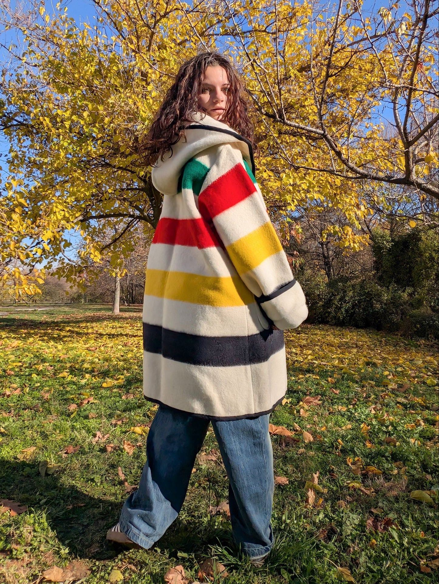 Woman standing backwards with a midi blanket capote coat or swing coat, made from handmade wool blanket.