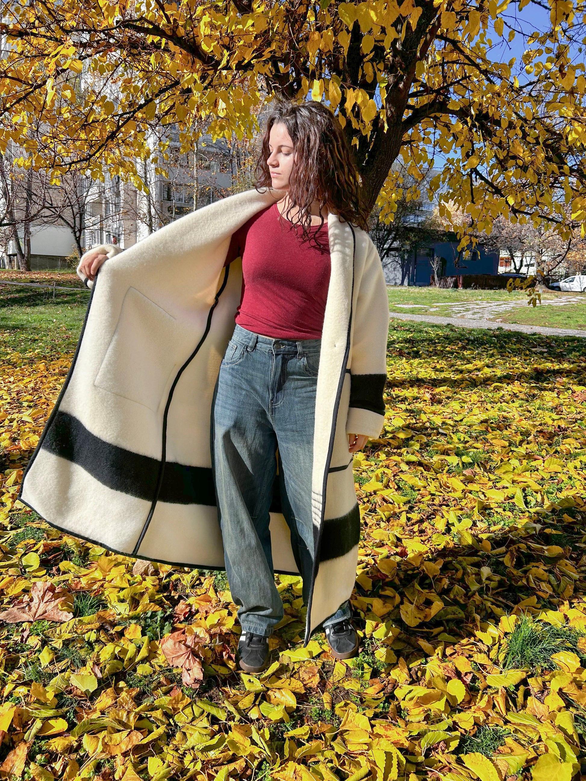 A woman is wearing a think long robe coat tailored from upcycled thick wool blanket