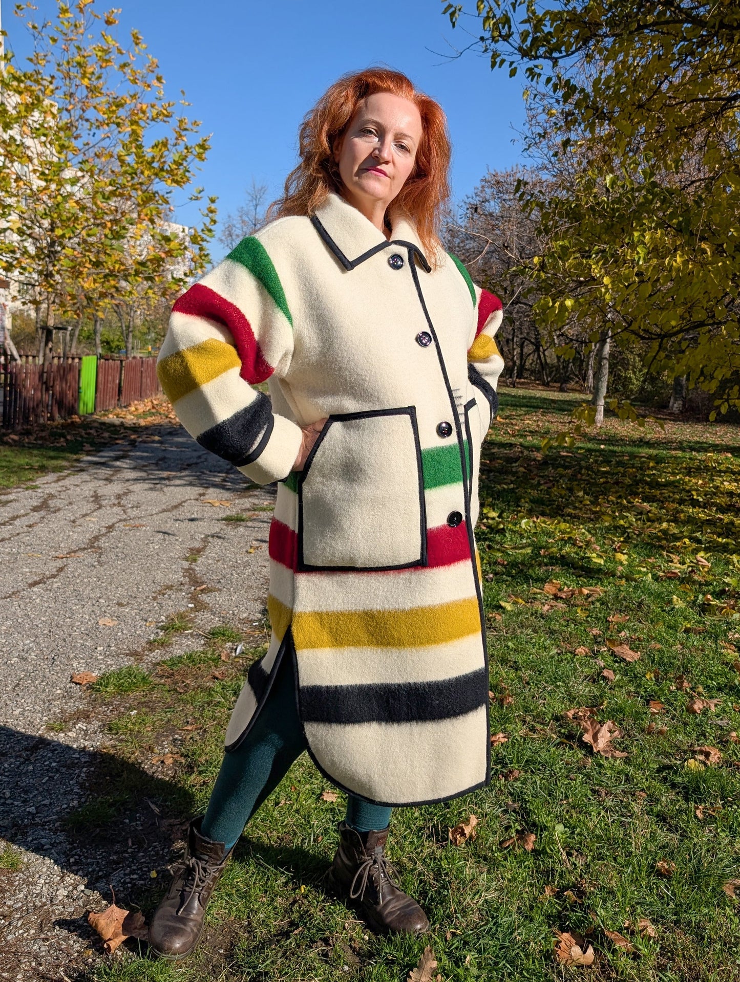 A woman wearing a classic collar duster coat with with single breasted button closure, side slits and two front pockets. Unisex model, thick pure wool outerwear.