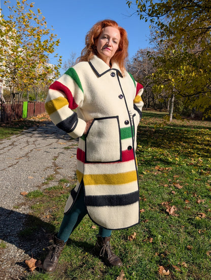 A woman wearing a classic collar duster coat with with single breasted button closure, side slits and two front pockets. Unisex model, thick pure wool outerwear.