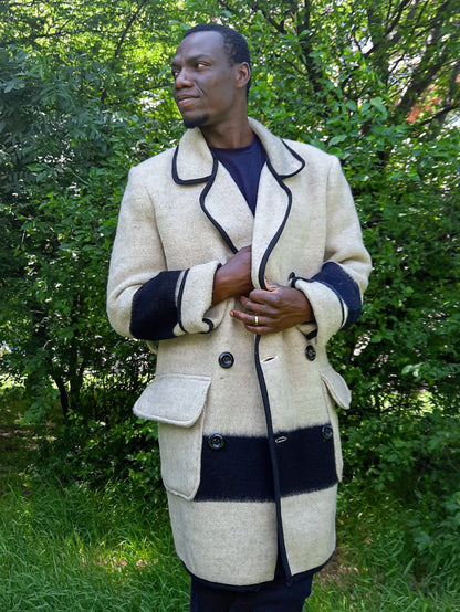 Man wearing a stylish slow fashion gray blanket coat with black stripes standing in a park.