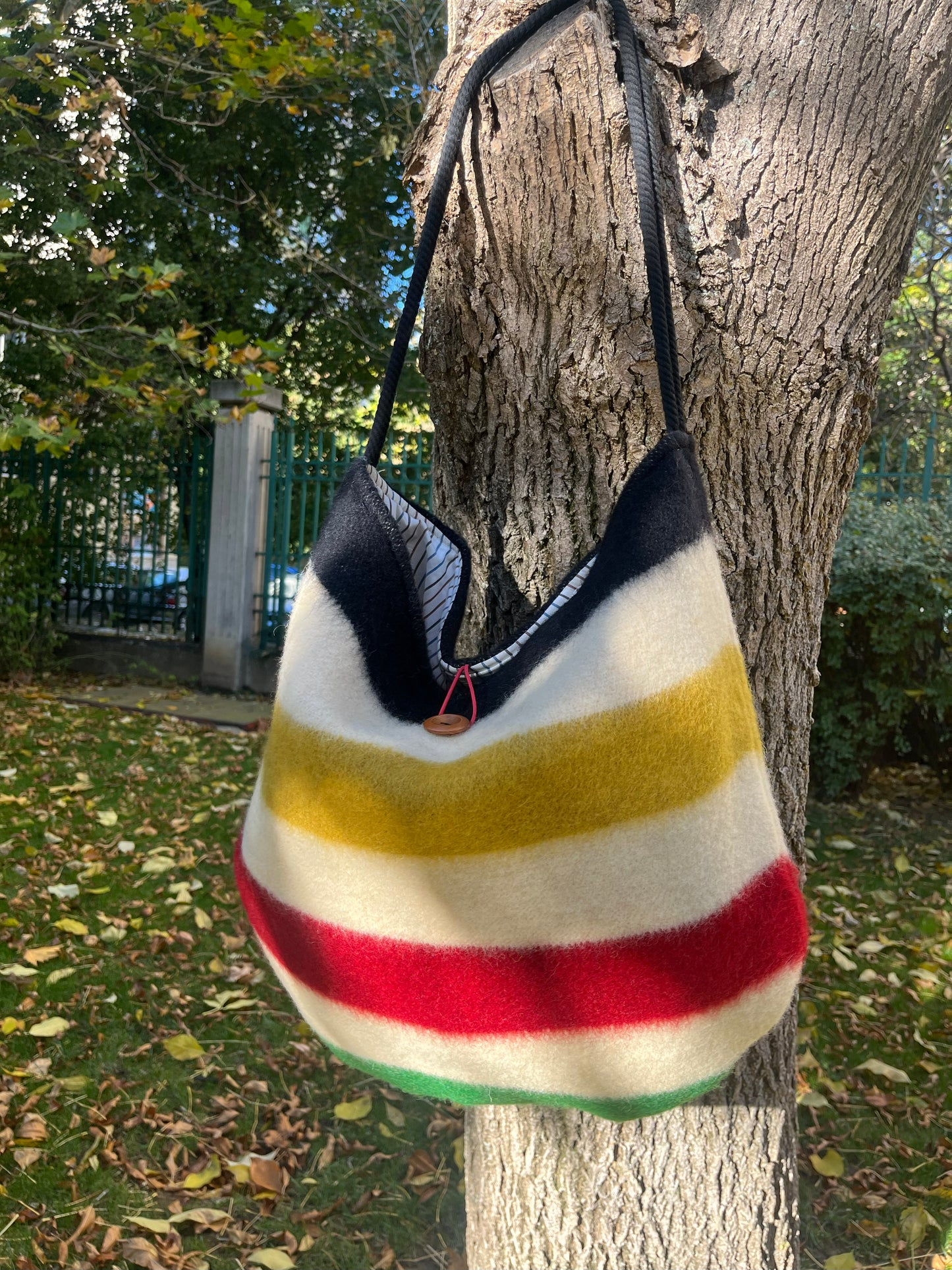 A modern boho shoulder bag hanging on a tree branch outdoors