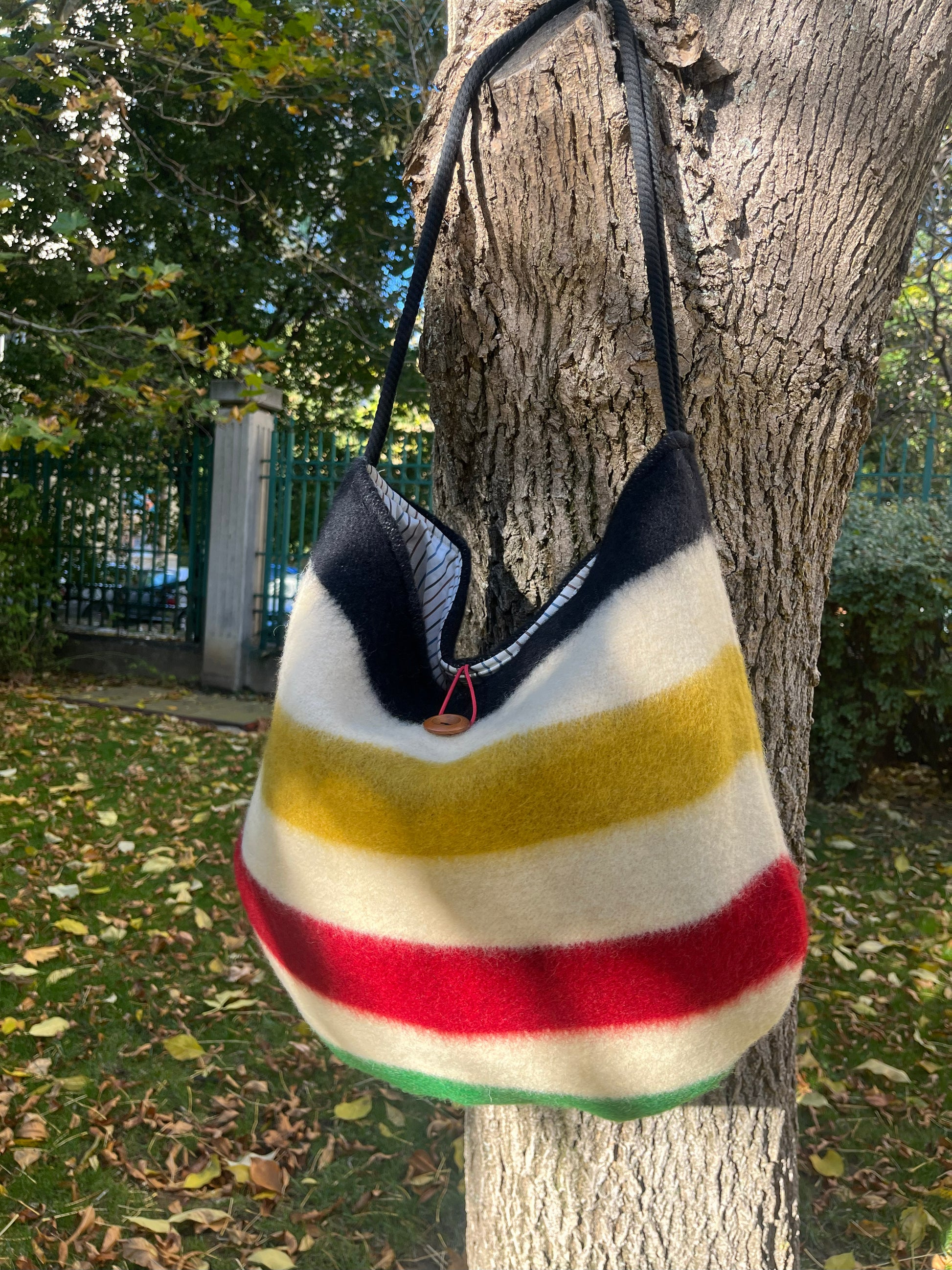 A modern boho shoulder bag hanging on a tree branch outdoors
