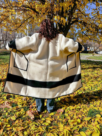 A woman wearing a loose kimono coat or statement coat out in a park setting