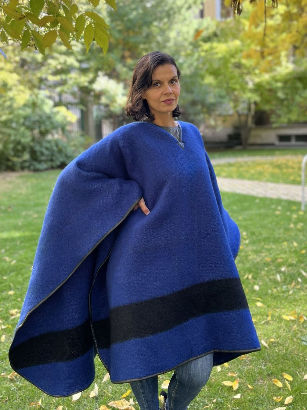 Woman wearing an oversized blanket poncho in indigo blue  with a black stripe.