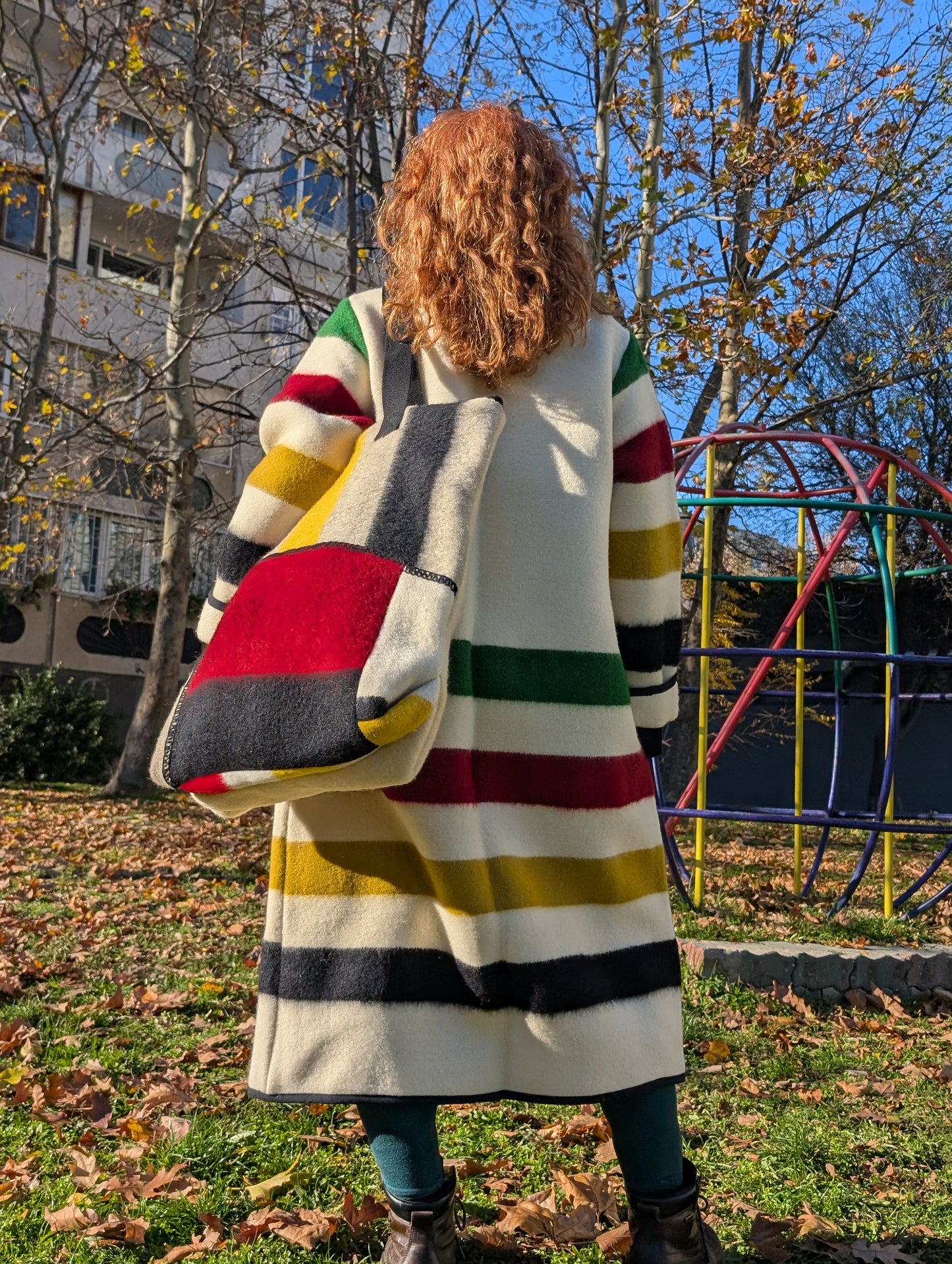 Woman wearing a classic duster coat with a large matching tote bag, both upcycled from all natural wool blankets, and looking fashionable and comfy.