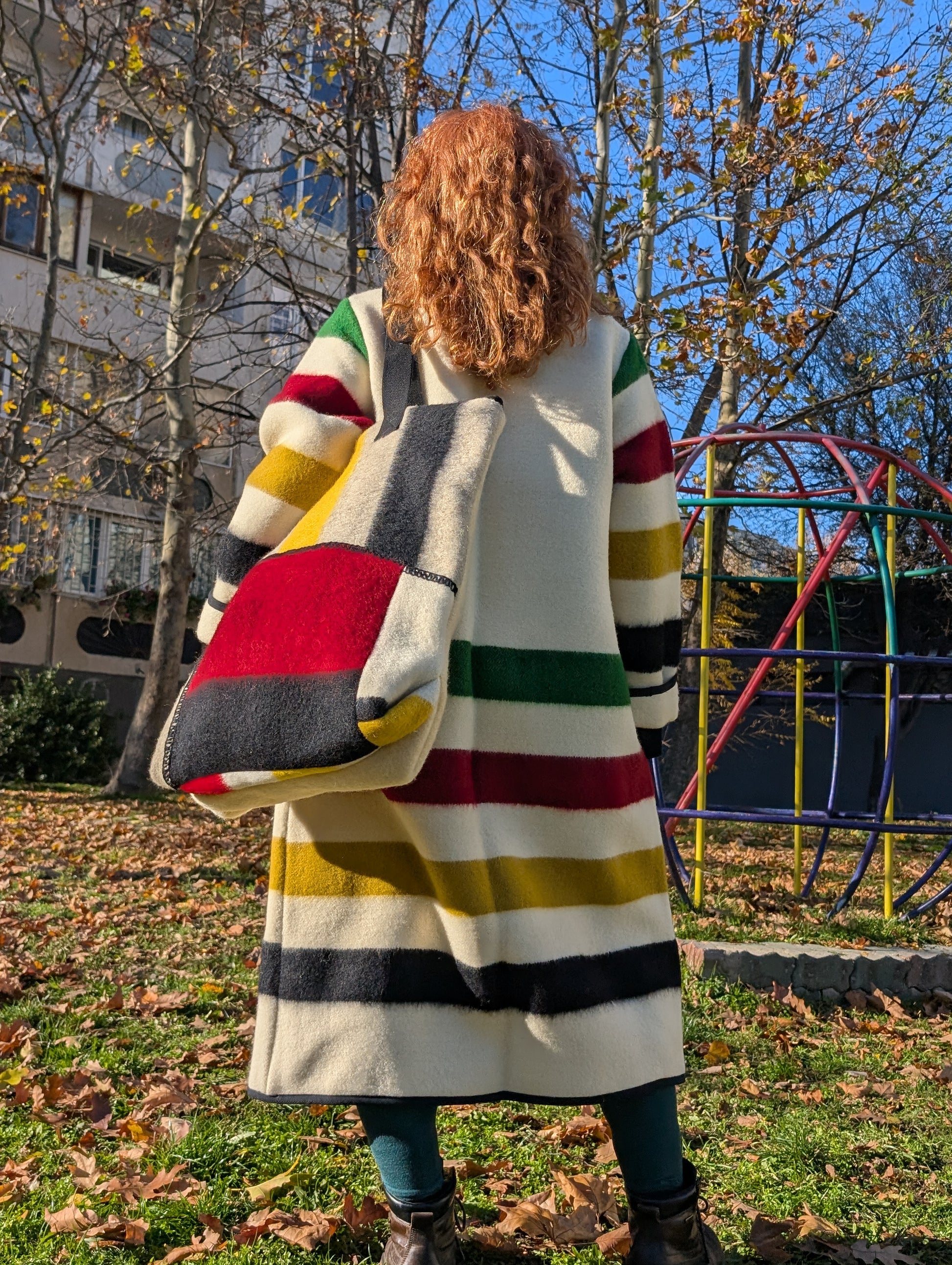 Woman wearing a classic duster coat with a large matching tote bag, both upcycled from all natural wool blankets, and looking fashionable and comfy.