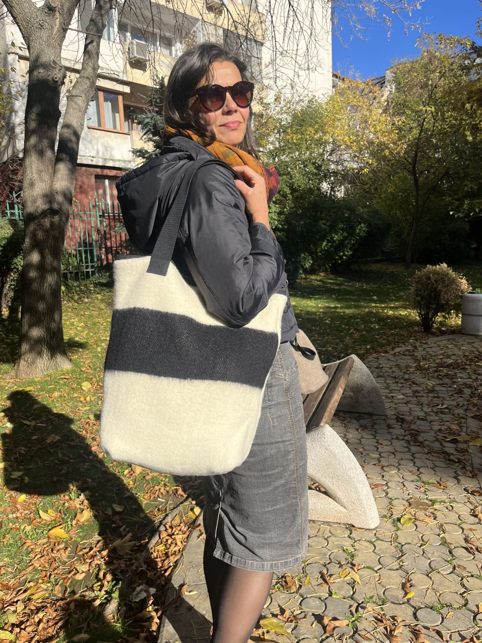 Woman holding a minimalistic stripe tote bag made of upcycled handwoven wool blanket.