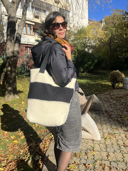 Woman holding a minimalistic stripe tote bag made of upcycled handwoven wool blanket.