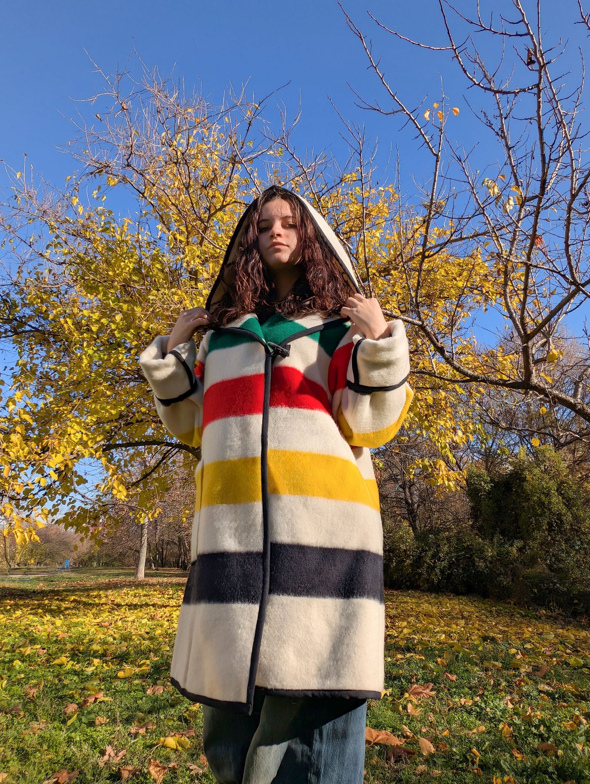 Woman wearing a colorful striped blanket swing coat in an autumn park