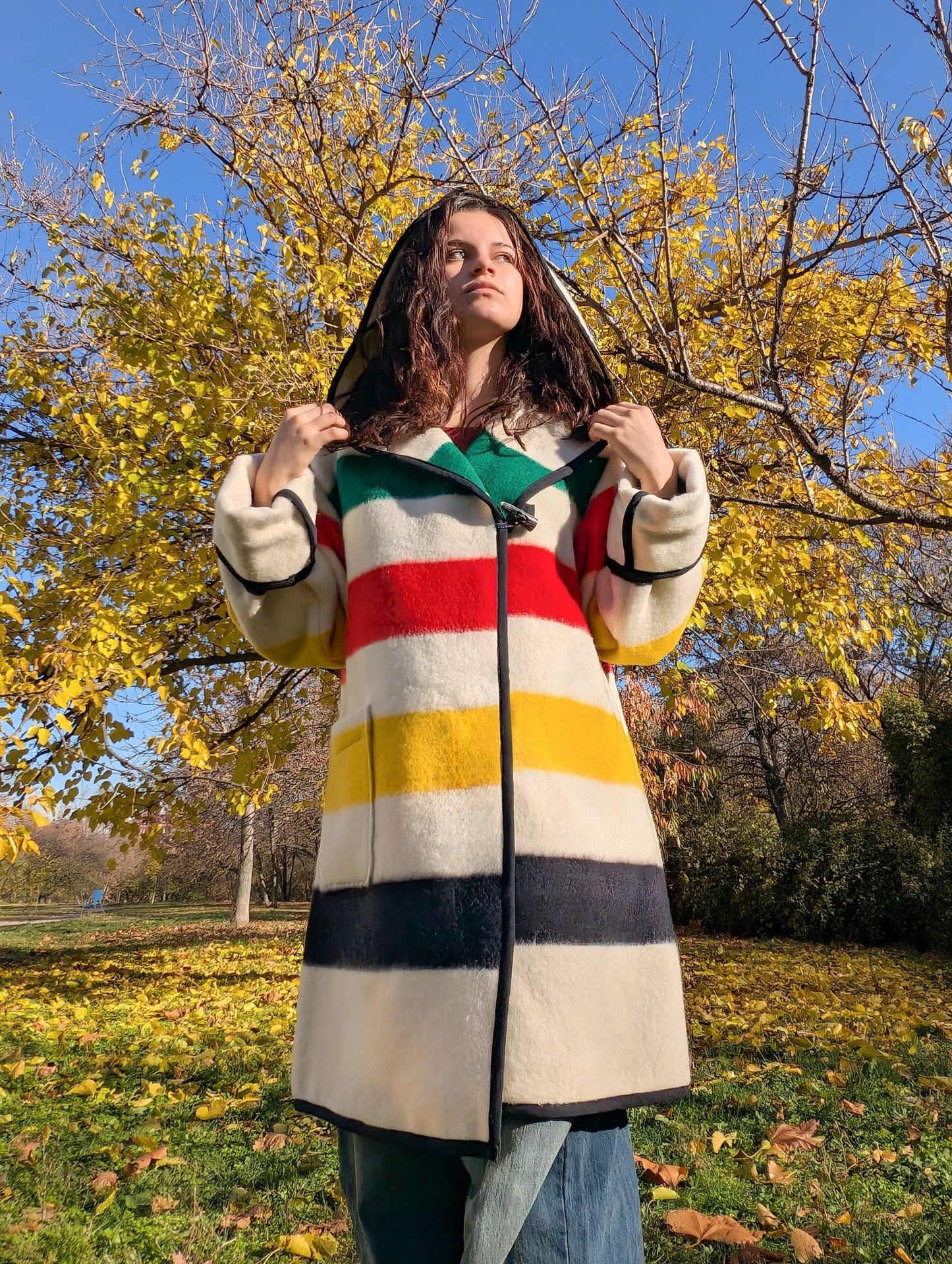 Person wearing a colorful swing capote coat with multicolor stripes