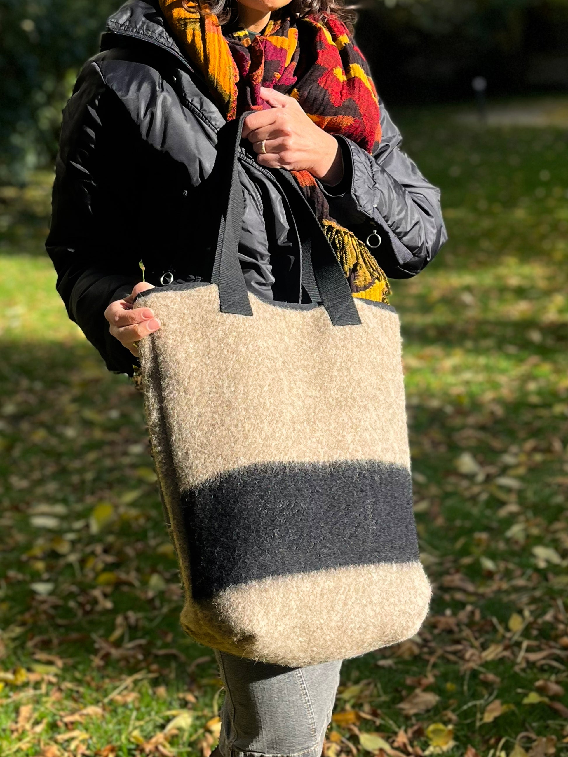 Woman holding an artisan handwoven wool blanket bag blending ethnic tradition, classic form and modern style. 