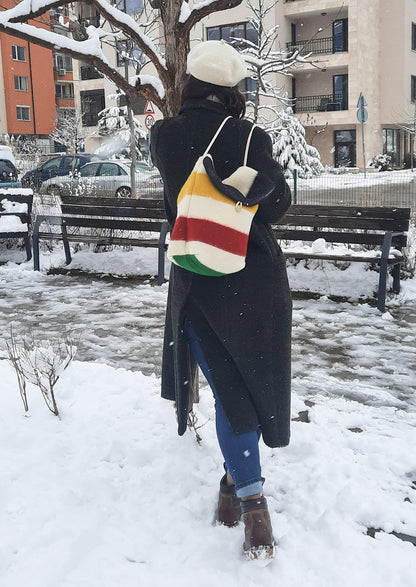 Woman walking in a snowy urban area with a colorful bag with ethnic weaven multicolor stripes, made of natural eco blanket.