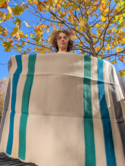 Person holding a large multistriped blanket made locally at a family studio.
