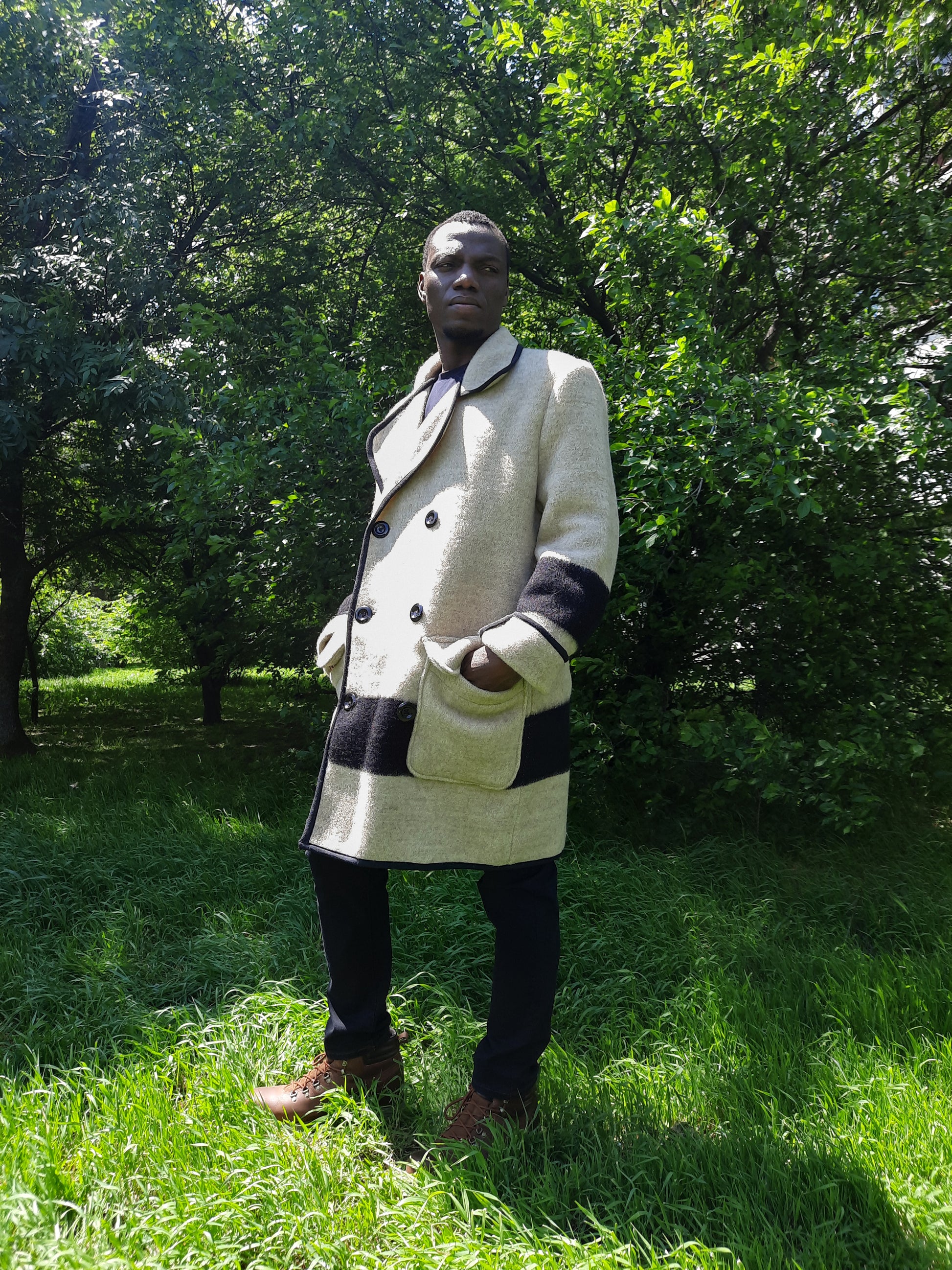 Man wearing a gray midi coat with black stripes, double breasted closure and peacoat collar.