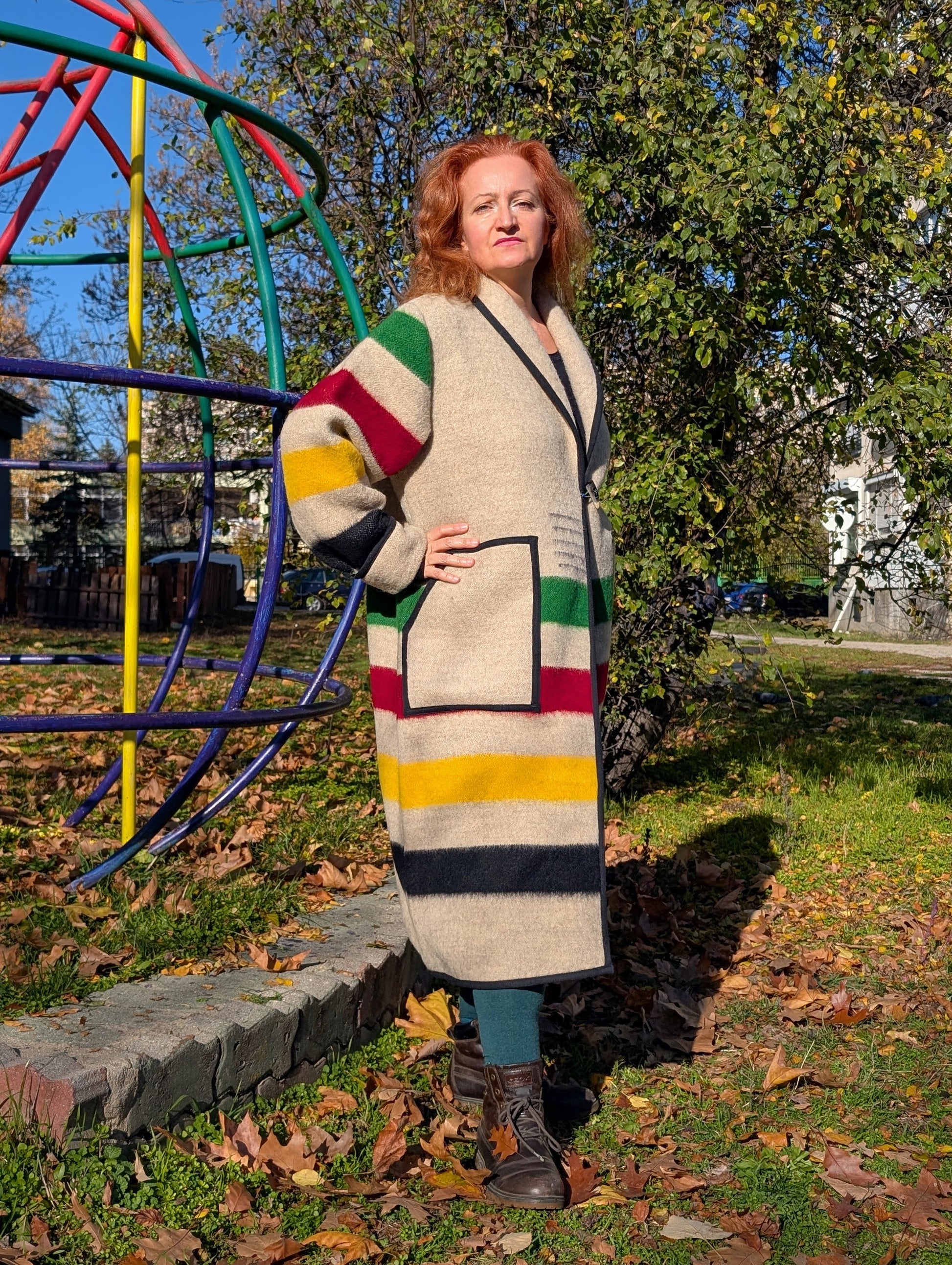 A woman wearing an oatmeal blanket capote coat with collar and striped pattern.