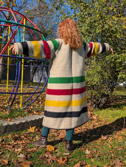 A ginger-hair woman showing her back while wearing a long blanket robe coat, cardigan coat with shawl collar, tailored from eco sustainable pure wool blanket.