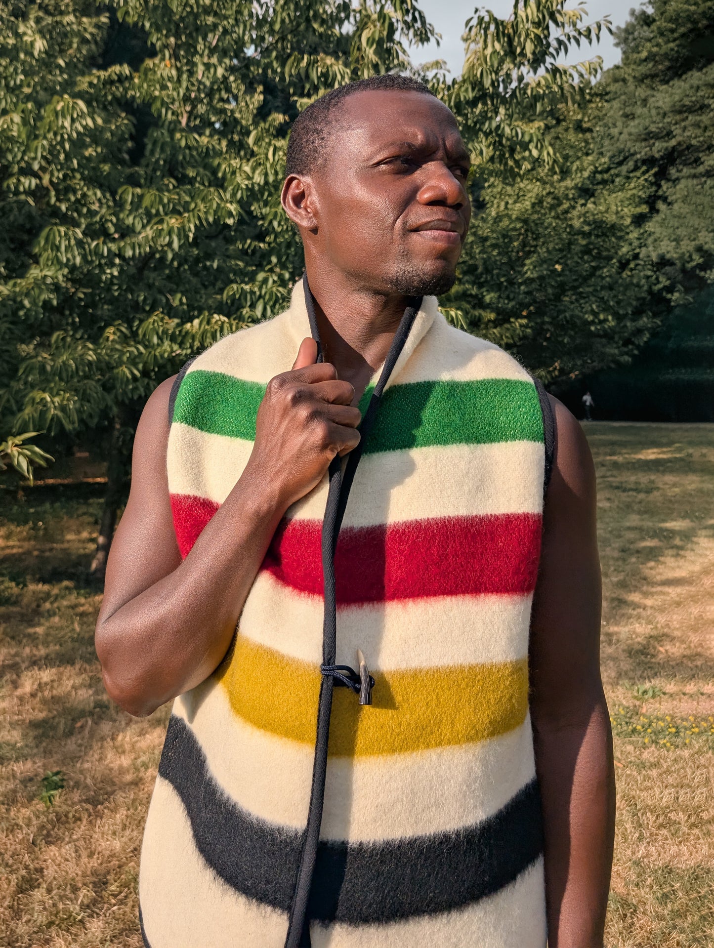 Man wearing a pure wool stripe vest jacket, handmade from wool blanket in a park-like setting 
