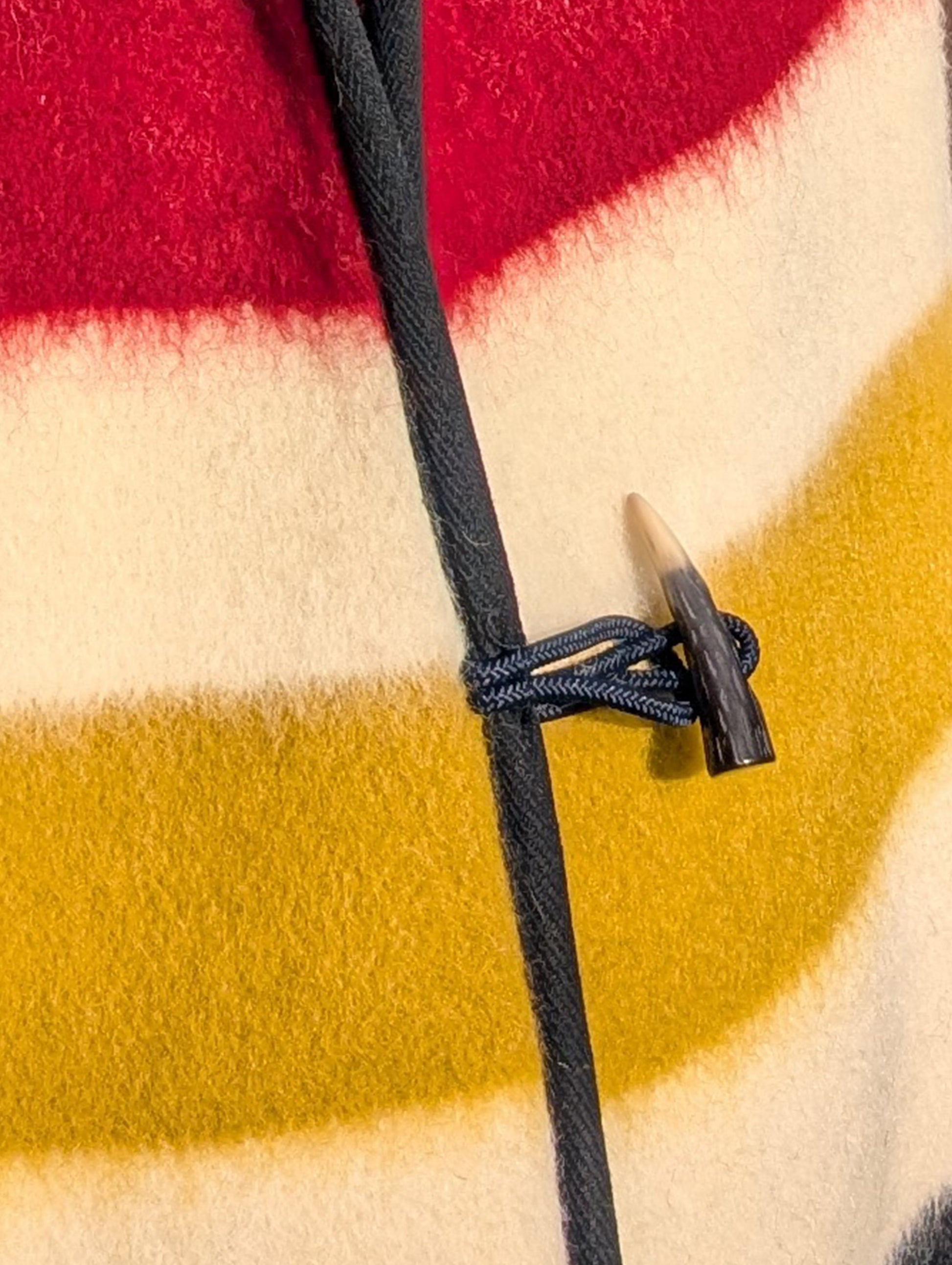 Close-up of a woolen multistripe wool vest with a drawstring and toggle closure. A colorful stripes pattern.