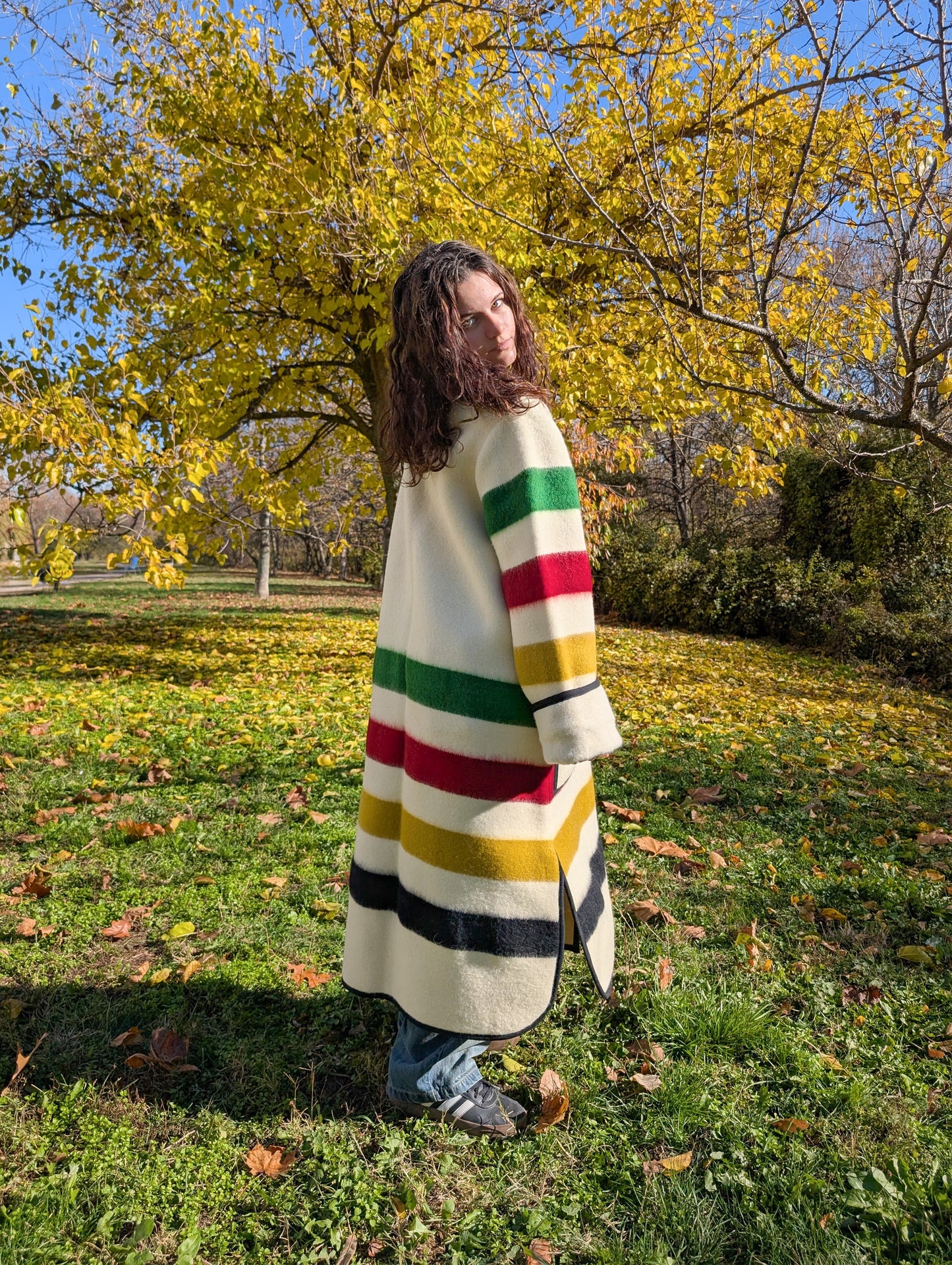A girl standing backwards and wearing a fashionable oversized single breasted duster coat with stand collar and two front pockets