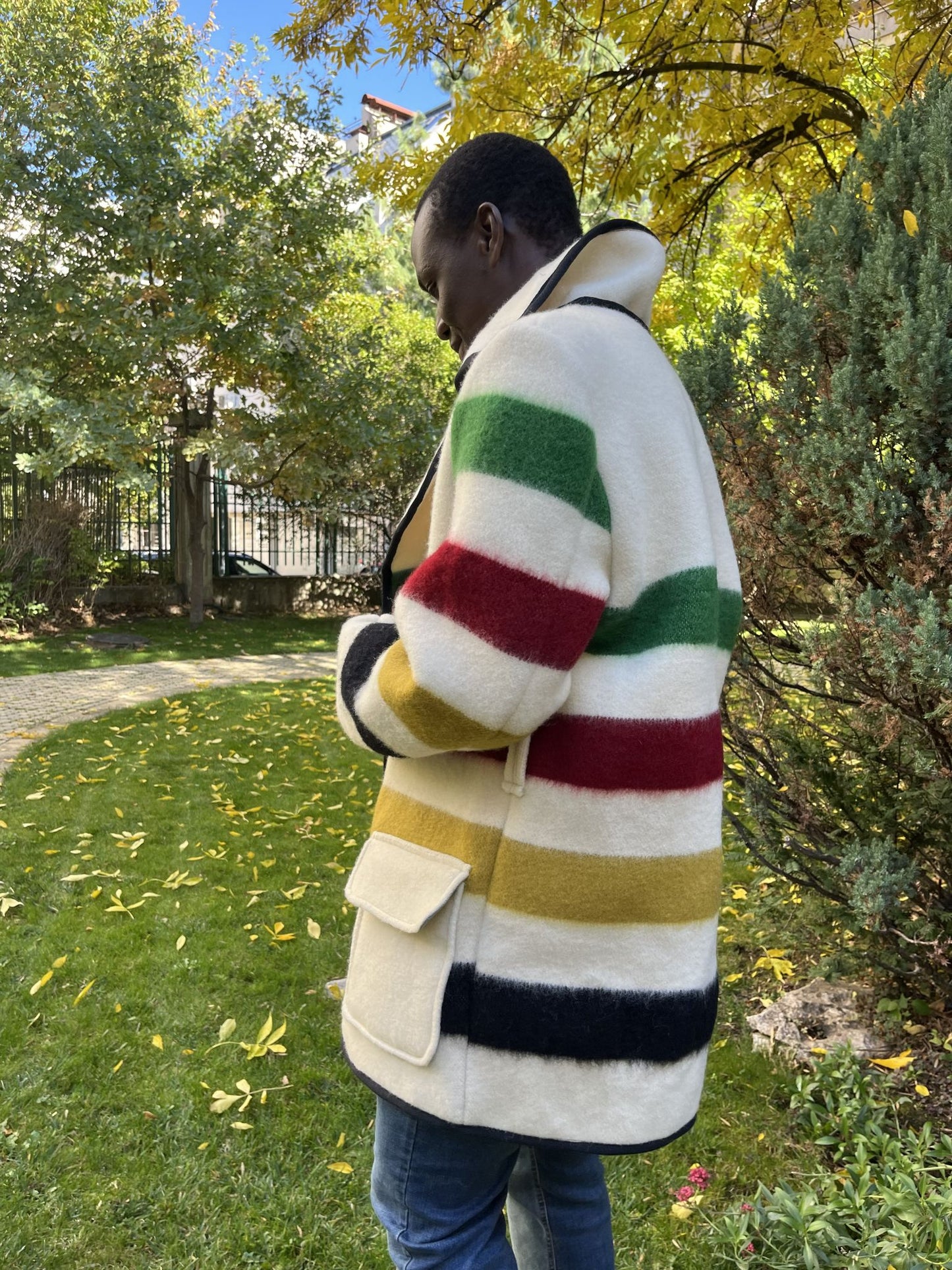 Person wearing a colorful striped coat and enjoying his style in a park setting