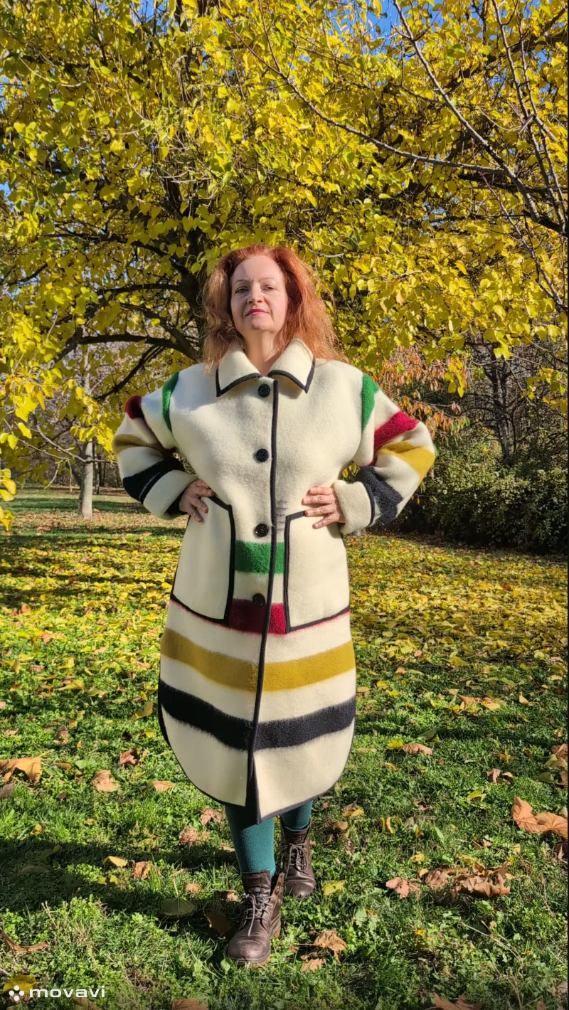 A woman wearing a blanket duster coat with with single breasted button closure, side slits and two front pockets. Unisex model, thick pure wool outerwear.