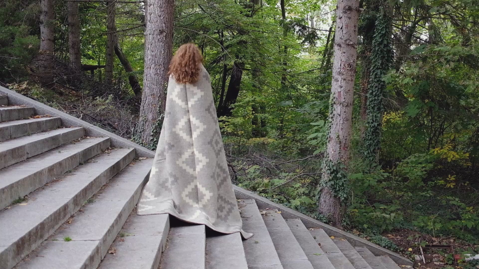 Video of woman unwrapping and draping an eco-luxury wool blanket with earth tones and ancient geometric design pattern. Ideal for modern and rustic home decors.