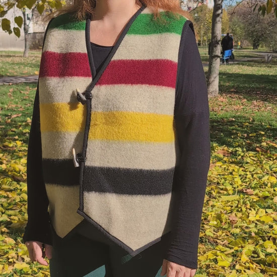 Video of a woman wearing a colorful striped sleeveless jacket, tailor made of repurposed virgin wool blanket.