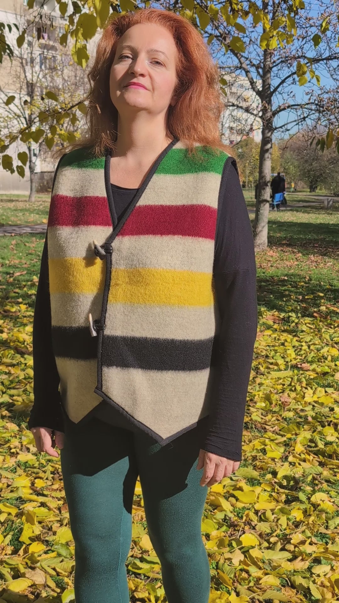 Video of a woman wearing a colorful striped sleeveless jacket, tailor made of repurposed virgin wool blanket.