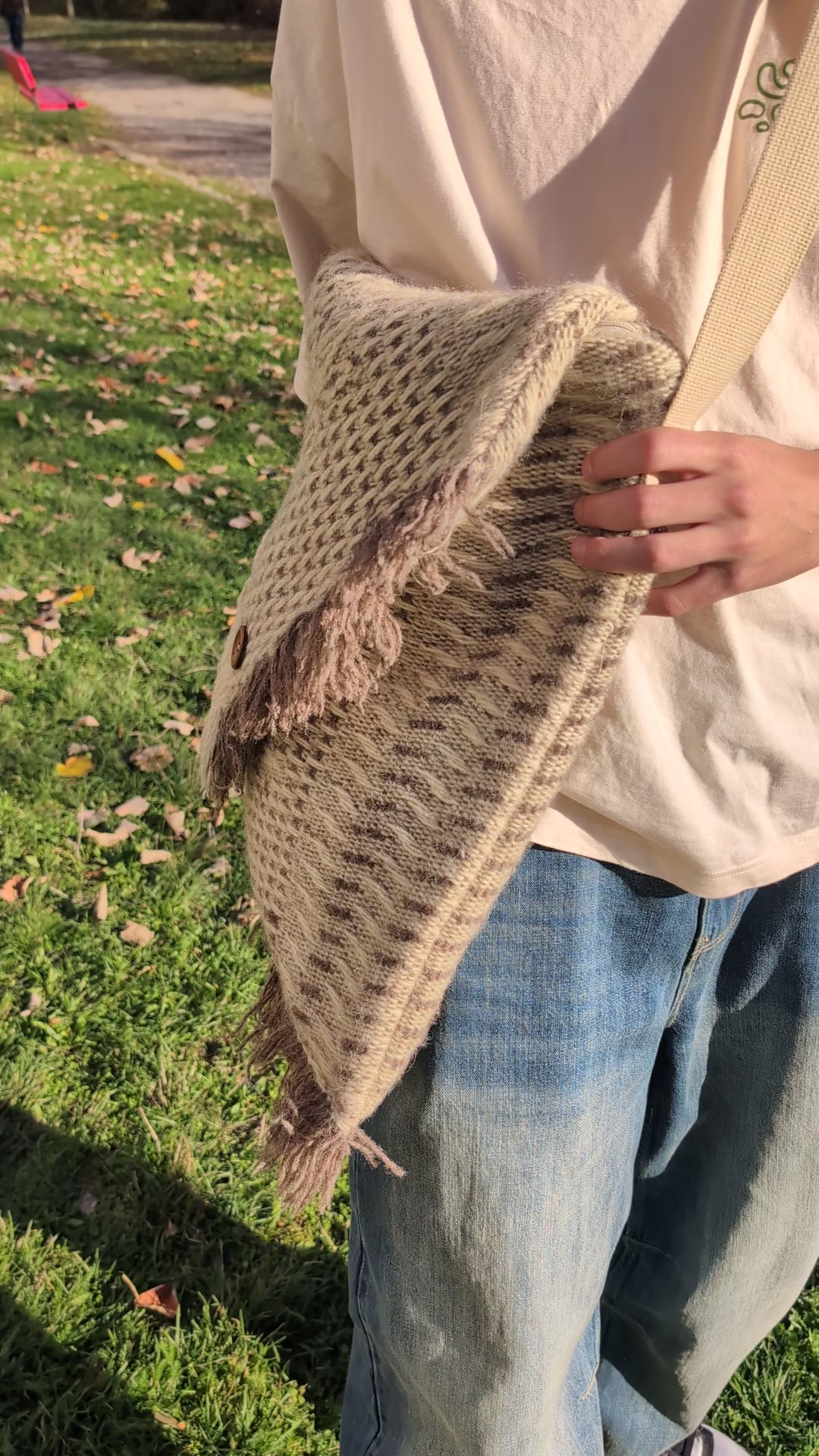 Person showcasing a wool blanket messenger bag with structured pattern and soft natural tones.